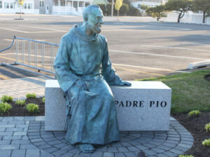 Padre Pio Statue Sitting on Stone Bench
